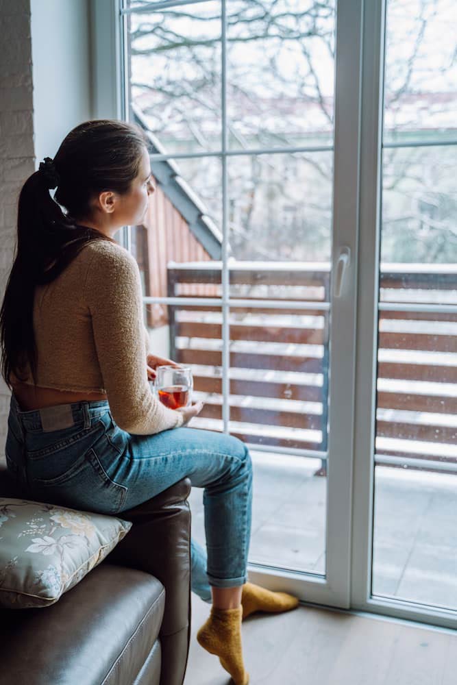 Woman Looking Out Window struggling with endometriosis pain
